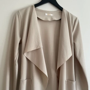 Beige kappa - Jättefin tunn beige kappa perfekt till vår och sommar, står ingen storlek men den passar Xs-S, möjligtvis M också! Knappt använd så väldigt bra kvalite!