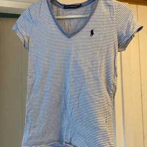 Ralph lauren t-shirt - Blåvit randig ralph lauren t-shirt med v-ringning! Har ett litet hål på 1 mm brett så absolut inget man kommar att se!!