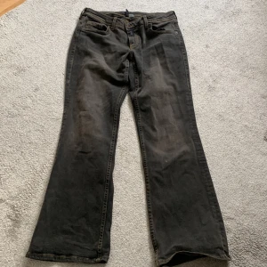 Snygga Lowwaist Bootcut jeans - Helt nya jeans från HM, endast testade. Säljer dom då dom är för små. Jättesnygg wash, svart/gråa med guldfärgad tråd.