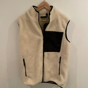 Fleeceväst - Trendig fleece väst som är helt ny med lapparna kvar. Köpt i början av 2024. Storlek S men sitter som M. Modellen är 176cm. Nypris 999kr. Vårat pris 449kr. Skriv vid minsta intresse!📩