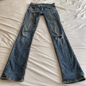 bootcut jeans från märket gul och blå från 2000-talet. lite slitna och har ett hål på knät