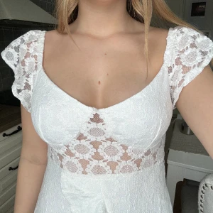 Studentklänning  - En oanvänd vit studentklänning i stl M med blommönster från Åberg Cøpenhagen. Orginal pris 1000 kr!!Jättefin passform och bekväm (behövs inte ha bh under). Säljer då jag beställde två från samma märke.