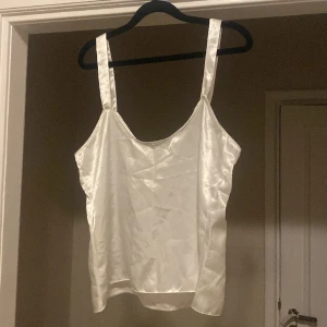Vitt linne - Glansigt vitt linne med lite bredare axelband. Vet inte vilken storlek men skulle gissa på M. Knappt använd
