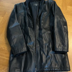 Skinnjacka  - Svart lång skinnjacka, använd några gånger, köpte secondhand, har ett hål på insidan av jackan men det är enkelt att fixa