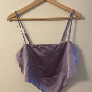 Festligt linne (oanvänt) - Festligt lila linne i glansigt material som är kantat på framsidan och har resår på baksidan. Mycket snyggt oxh knappt använt!