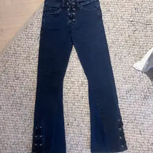 Jättefina mörkblåa utsvängda jeans med snörning både upptill o nertill. Innebenslängden är 69cm o midjemått rakt över är 31cm. Tyväär för små så säljer💓