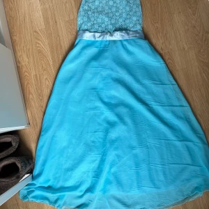 Blå fin klänning - Blå klänning som blivit använd en gång under en skolavslutning. Spets överdel med band som man antingen knyter fram eller bak. Kan ge mera specifika mått till den som vill!