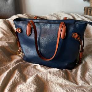 En liten fin marinblå väska i vintage stil. Knappt använd och i bra skick. Den är gjort av läder, däremot osäker på om det är äkta eller fake. Ca 18x30 cm. Axelbandet finns tyvärr inte. Köpare betalar frakt