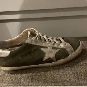 Golden goose skor - Säljer mina golden goose skor i färgen grön. Skorna är i något slitet skick med ett litet hål på utsidan av skon som man ser på bilden. Nu pris 5900 men på grund av skicket mitt lägre pris.