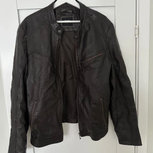 Mörkbrun skinnjacka  - Storlek 48 vilket motsvarar M/L. Fint skick, dock hål i innertyget under ena armen men inget som påverkar funktion. Riktigt skin. 