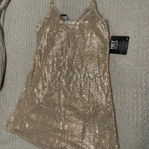 GLITTER KLÄNNING MED PRISLAPP - Helt ny klänning från Nelly! Aldrig använd med prislapp kvar! Jätte snygg med lårhögaboots till eller bara som den är! Passa på! 