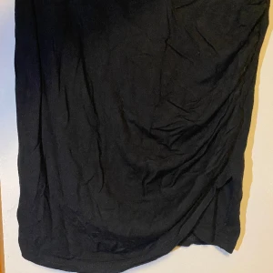 Svart tight kjol - Svart tight kjol med ett mjukt stretchigt material, fin att ha till fest eller till sommaren utan att vara obekväm. Fin överlapps detalj