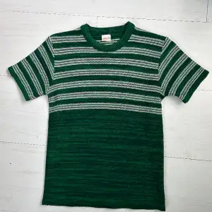 Grön stickad T-shirt i 100% akryl. Köpt second hand :). Storlek L men passar även mig som har storlek M, beroende på hur man vill att den ska sitta