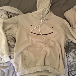 Grå hoodie med tryck - Super söt smiley hoodie i en krämgrå färg. Har filtloknande gosigt material på insidan super mjuk. Nyskick aldrig använd, inga nopprar fläckar skador som helst. S sitter oversized, pris går o diskutera 