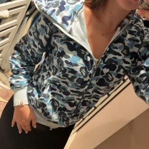 Bape hoddie  - Säljer denna bapehoddie som jag köpte här på Plick för ett år sedan för 1200kr. Jag har inte använt den speciellt mycket men den har en fläck på armen. Jag har kvar påse och etikett som jag fick med. 