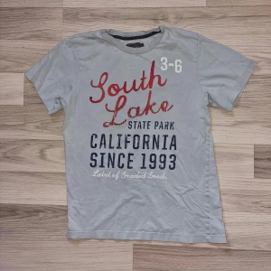 T-shirt  - Ljusblå T-shirt från H&M I stl 158/164, har ett litet hål på "bröstet", se bild, annars hel. 