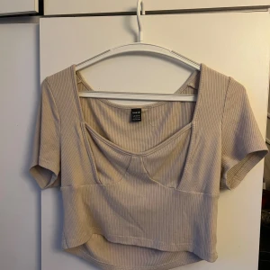 Beige ribbad topp från Shein - En beige ribbad topp från Shein i storlek L (40/42 EU, 8/10 US). Toppen har korta ärmar och en fyrkantig urringning. Den är croppad och har en tight passform.