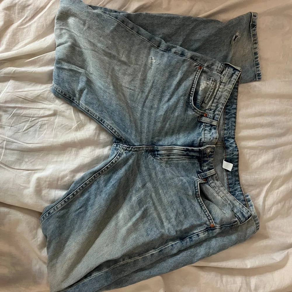 Blå raka lågmidjade jeans i storlek 42 från H&M. De har hål som ska vara där förrutom ett vid benet som syns på bilden.. Jeans & Byxor.