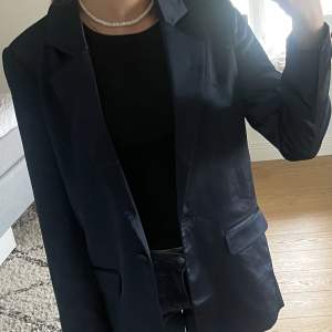 Blazer/ kavaj i mörkblå satin material, lite over-sized i modellen. Aldrig använd, den är inte uppsprättad i bak eller vid armarna. Strl xs men passar även s Märket är Second Female 