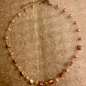 Barnhalsband med sötvattenspärlor  - Kortare halsband för barn med sötvattenspärlor och snäckskal. Vet ej om använt, i perfekt skick, inget att anmärka på. 