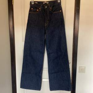 Ett par mörkblåa Levi’s Ribcage Wide Jeans i storlek 28. I superbra skick och ungefär helt oanvändna.