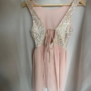 Balklänning 36  - Kort balklänning med djup ringning i ryggen och paljetter med spets på överdelen. En mindre knappt synbar fläck i nederkanten baktill, se sista bilden. Obs. klänningen är något kort på mig som är 173. 