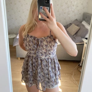 Somrig topp - Somrig topp med rosett fram och volanger. Står ingen storlek men psssr S-L beroende på hur man vill att den sitter. 