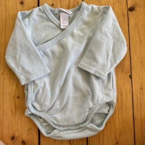 Omlottbody  - Blå omlottbody i storlek 62, från H&M. Bra skick men lite nopprig