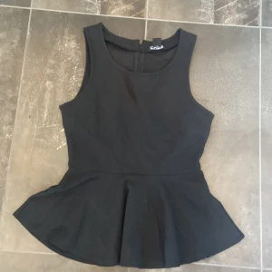 Svart topp - Svart topp i strl xs från monki. Jätte fin topp och skönt material. Den har en volangdel på nedre delen av toppen och en dragkedja där bak. Den är i jätte bra skick då den är använd.