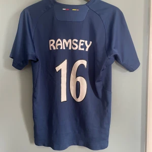 Fotbollströja Arsenal Aaron Ramsey jersey - En arsenal tröja med den walesiska spelaren Aaron ramsey som bl.a. är känd för sin insats i en 2016 där Wales tog sig till en historisk semifinal, tröjan skick: 6/10 därav lågt pris, kom gärna med eventuella frågor!🏴󠁧󠁢󠁷󠁬󠁳󠁿🤝