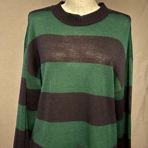 Randig stickad tröja från H&M - Säljer en mysig randig stickad tröja från H&M i grönt och svart. Tröjan har långa ärmar och en ribbad rund halsringning. Perfekt för höst och vinter! 🖤💚