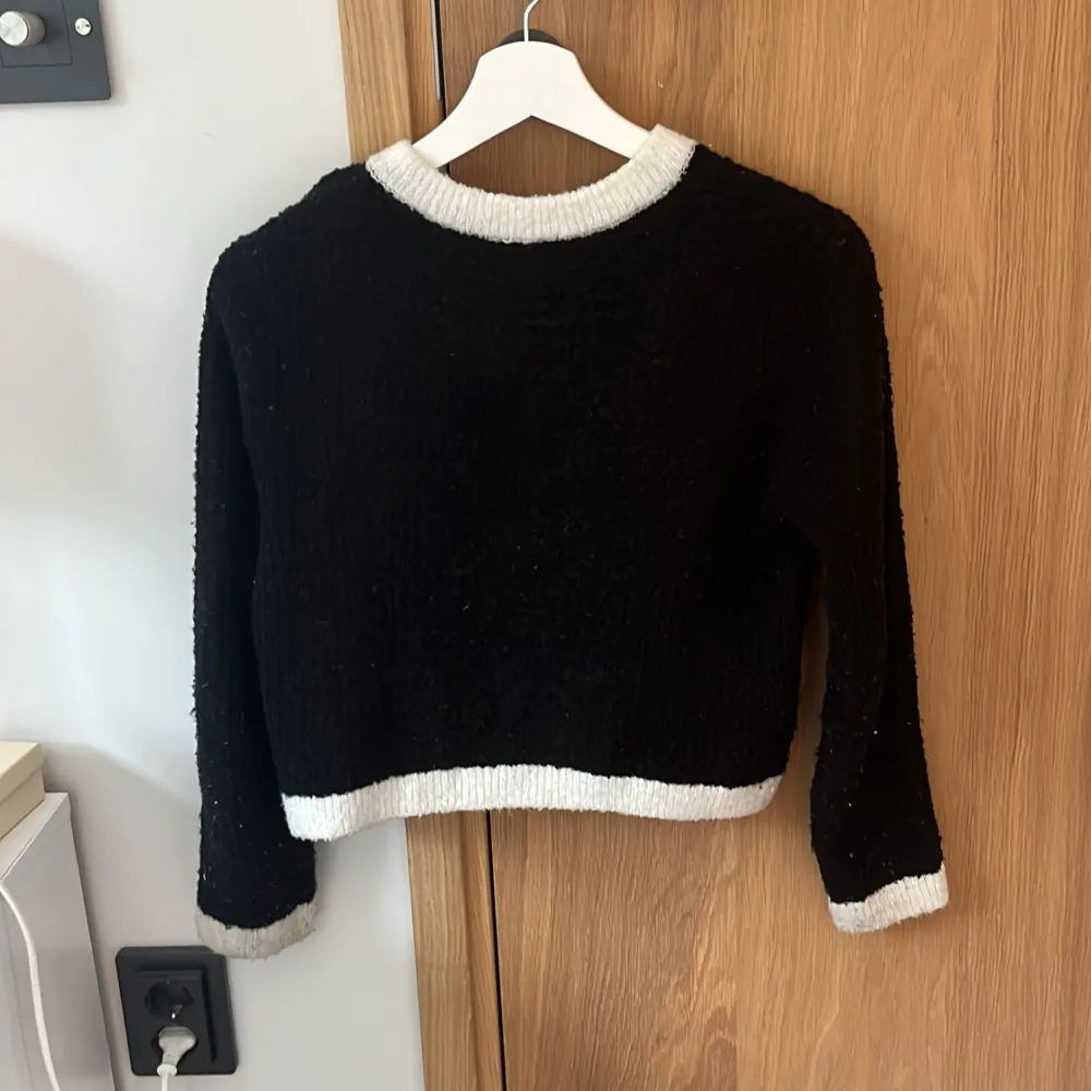 Säljer en snygg svart och vit kofta från H&M. Den har långa ärmar och är dekorerad med fina knappar framtill. Koftan har vita detaljer vid kragen, ärmsluten, fickorna och nederkanten. Perfekt för höst och vinter!. Neuleet.