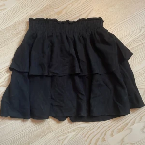 Svart kortkjol från Princess Polly - Säljer en superfin svart volangkjol från Princess Polly i storlek XS (EU 34). Köpte i USA för cirka 500kr och är knappt använd💕