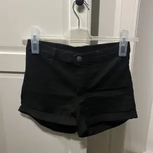 Ett par svarta shorts från H&M Divided. Shortsen har en knapp och dragkedja framtill samt uppvikta benslut.