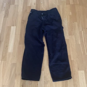 Svarta byxor från H&M - Svarta byxor från H&M med justerbar midja. Byxorna har en baggy passform och är utrustade med både fram- och bakfickor.
