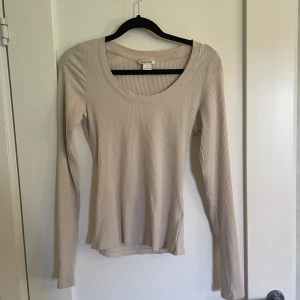Beige ribbad tröja från Michael Kors - Säljer en superfin beige ribbad tröja. Den är långärmad och har en rund U-ringning. Den är i nyskick! Materialet är mjukt och stretchigt, vilket gör den väldigt bekväm att ha på sig. Köp den nu eller ge ett bud! 