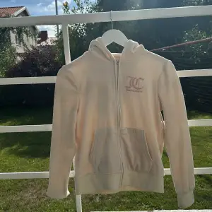 Mjuk hoodie i vit sammet med rosa metallic tryck från Juicy Couture. Endast använd fåtal gånger. 