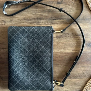 Malene Birger väska - Svart/grå med guld detaljer.  Axelremmen lite trasig högst upp. Går enkelt att byta till ett nytt band.  Bredd: 25,5 cm Höjd: 18cm Nypris 899kr 