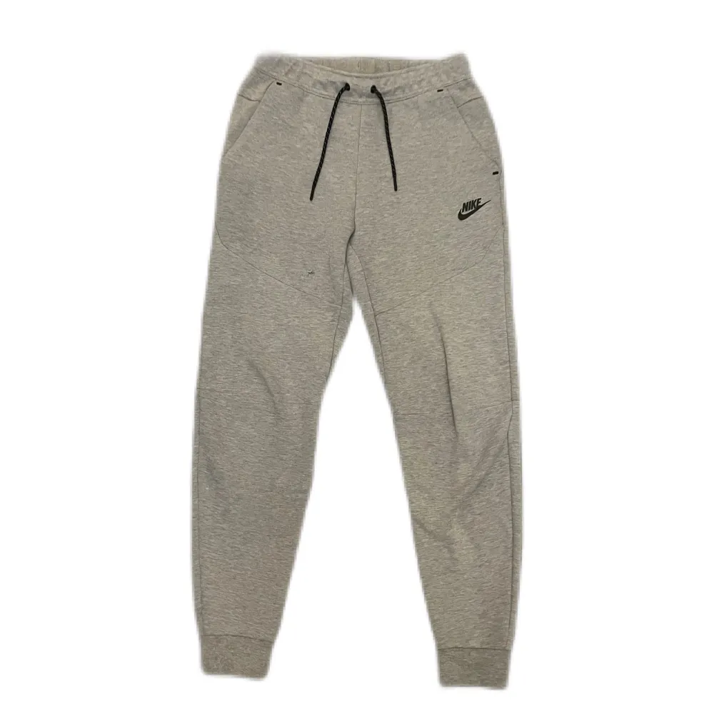 Säljes: Nike Tech-byxor i storlek XS. Skick: 5/10 med ett litet hål vid låret. Enkelt att fixa. . Jeans & Byxor.