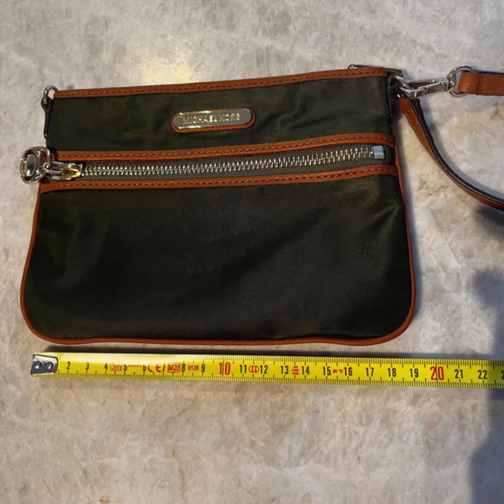 Just enough room for ID , cards & phone What more do you need?  Khaki green nylon trimmed in genuine leather & leather strap. The bag can be worn in 2 different ways.  It’s unused. Closure: zip Lining material: fabric. Väskor.