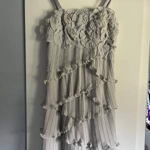 Otroligt fin klänning med volanger och fina detaljer! Går att ha exelbandslös och det finns en gömd dragkjedeja på ena sidan.🌸 ljusljus grå/vit