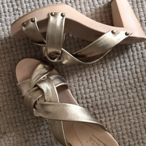 Träskor med guldfärgat kalvskinn, stl 39 - Sköna, extremt lätta clogs, 9 cm klack i mjukt guldfärgat kalvskinn, stl 39. Helt nya. 
