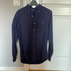 Mörkblå Ralph Lauren skjorta - Mörkblå Ralph Lauren skorta. Storlek: M, Classic fit. Skick: 8,5/10. Kontakta oss för fler bilder eller info!🙌