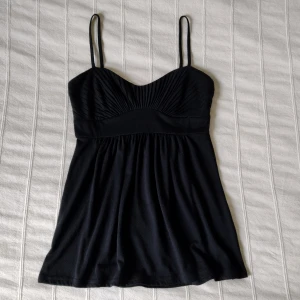 Svart topp/linne, storlek XS 🖤 - Svart topp som är så fin. Den är fodrad över brösten och med skenor, som gör att den sitter jättebra, även utan bh. Storlek XS. Tyget är lite smånopprigt. 