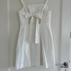 Cos vit klänning - Vit kort klänning från COS i storlek 38. Öppen rygg med band som kan knytas som man vill. Stilren och väldigt fint skuren! Dragkedja i sidan. Helt oanvänd med lappen kvar, endast testad. Säljer då jag köpte två storlekar. Nypris 790kr! 