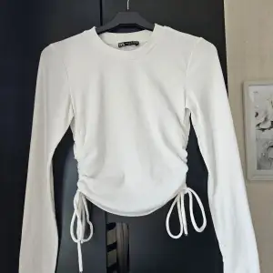 En vit tight tröja med snören från Zara i storlek S. Den är i bra skick. 97% polyester 3% elestan
