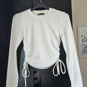Vit tröja med snören - En vit tight tröja med snören från Zara i storlek S. Den är i bra skick. 97% polyester 3% elestan