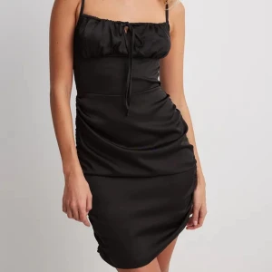 Svart klänning  - Säljer denna svarta satinklänning från NAKD. Stl 36. Justerbara band. 