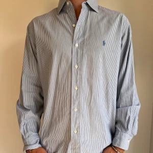 Ralph Lauren skjorta  - Blå randig Ralph Lauren skjorta i storlek 16,5 vilket motsvara ca XL. Skjortan är i fint skick utan några skavanker. Modellen är 186 cm lång. Orginalpris ca 1500 kr och nu endast 499. 