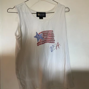 Linne med USA motiv  - Vitt linne med USA flagga. Mycket bra skick då den knappt är använd. Storlek S men i oversize modell så snarare en M/L 